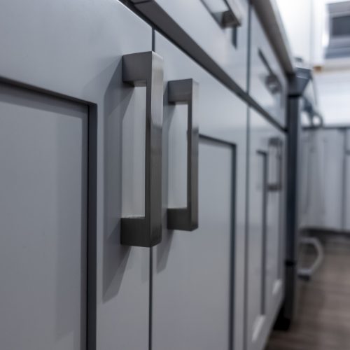 Closeup of gray kitchen cabinet with matching gray handles.